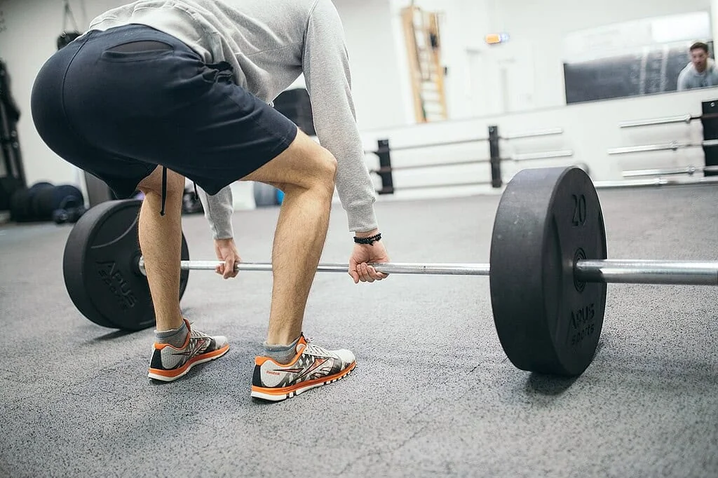 Athlète soulevant des poids en salle de sport soulignant l'importance de la nutrition