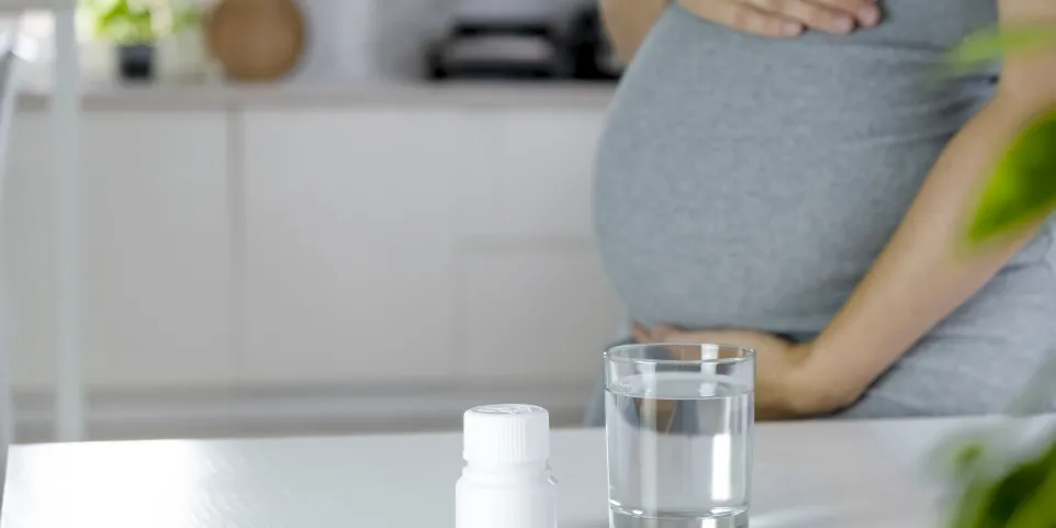 Femme enceinte consultant les étiquettes de vitamines prénatales en pharmacie