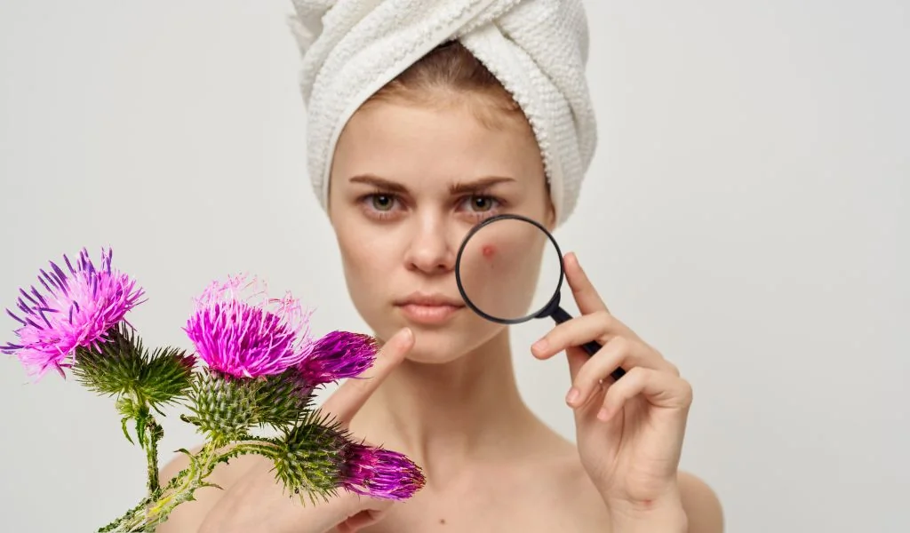 Femme examinant sa peau saine après un traitement au chardon marie pour l'acné