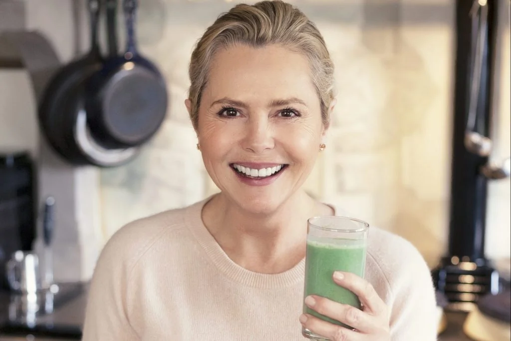 Femme souriante buvant un jus à la chlorella pour augmenter son taux de fer