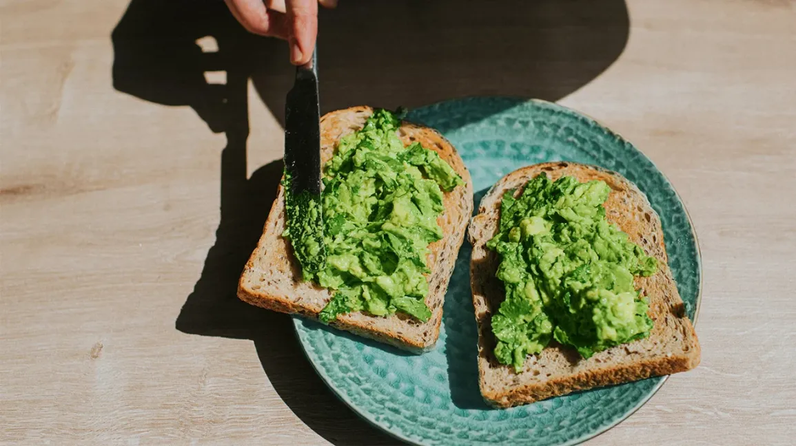 Préparation d'un avocado toast avec de l'avocat frais sur du pain complet