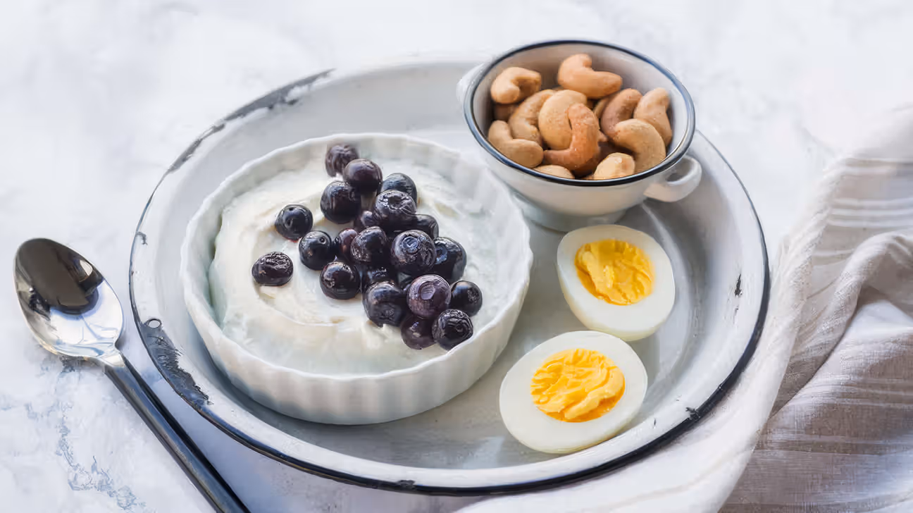 Assiette bento avec yaourt, œuf dur, myrtilles et noix de cajou