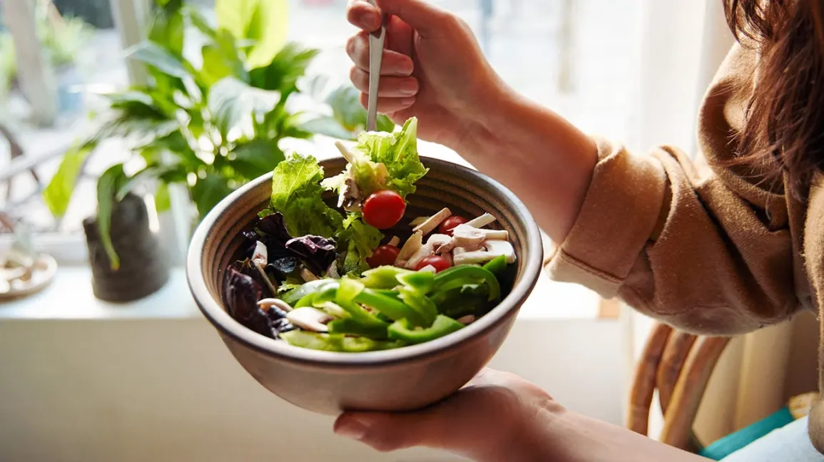 femme mangeant une salade fraîche dans un bol
