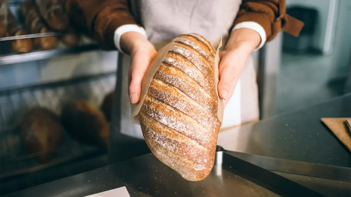 Main tenant une miche de pain à base de blé