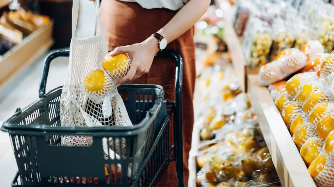 Une personne choisissant des pamplemousses au supermarché