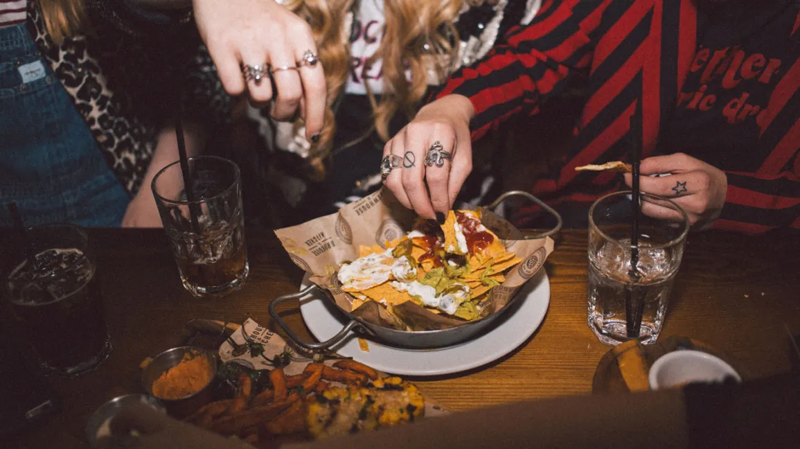 Mains essayant d'attraper des nachos dans un bar