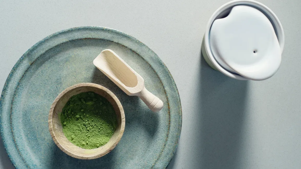 Poudre de matcha et cuillère en bois sur une assiette bleue