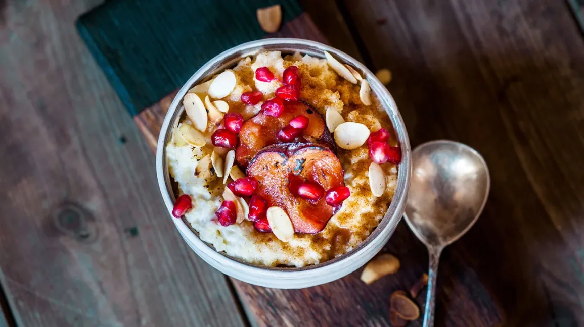 Porridge de millet avec prunes rôties, grenade et éclats d'amandes