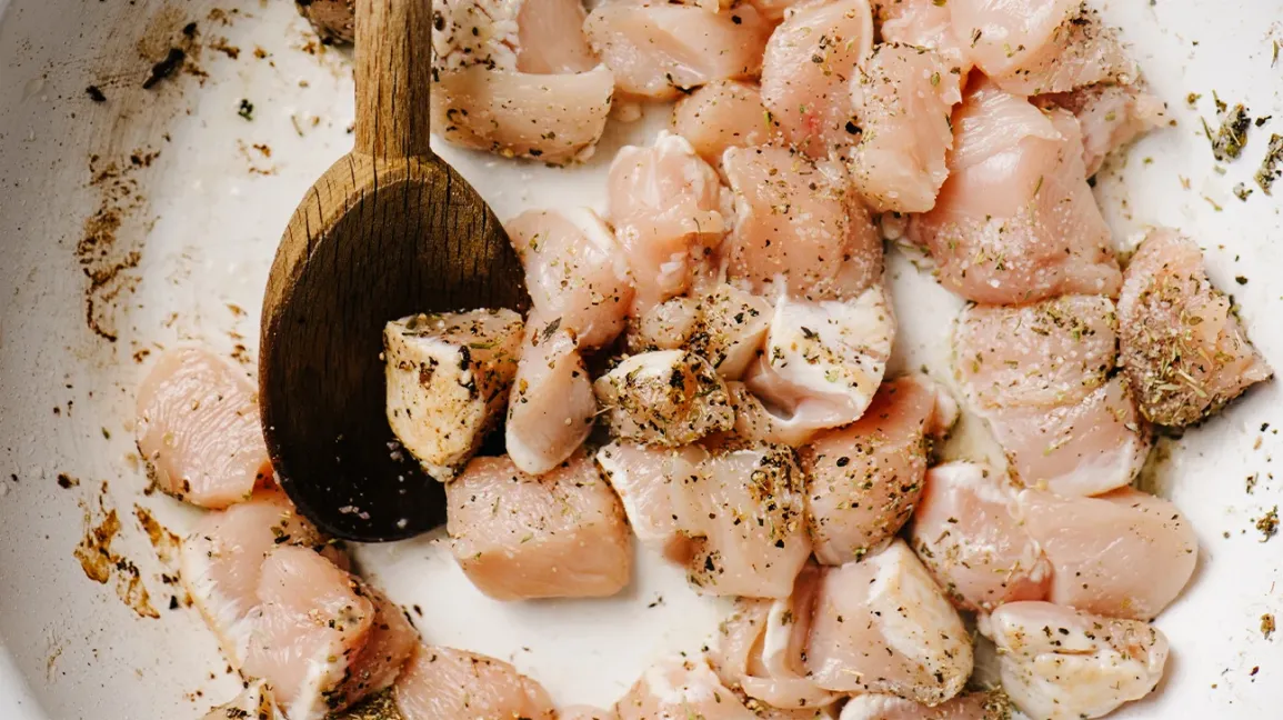 Morceaux de blanc de poulet cru dans une poêle