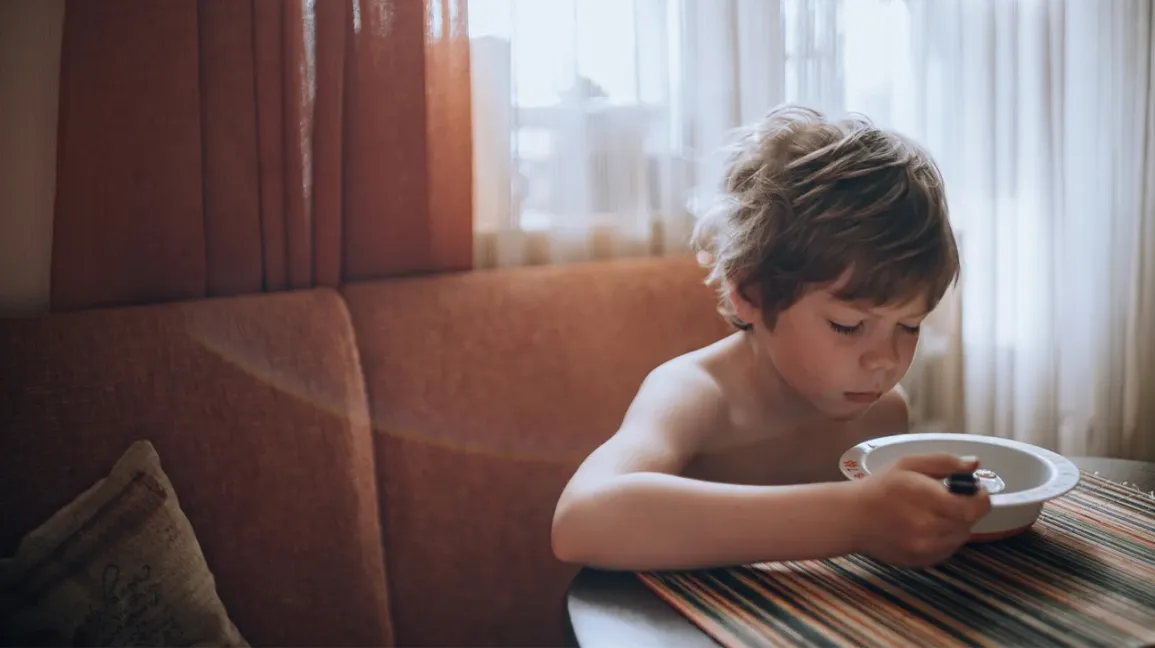 Enfant malade mangeant une soupe à la cuisine