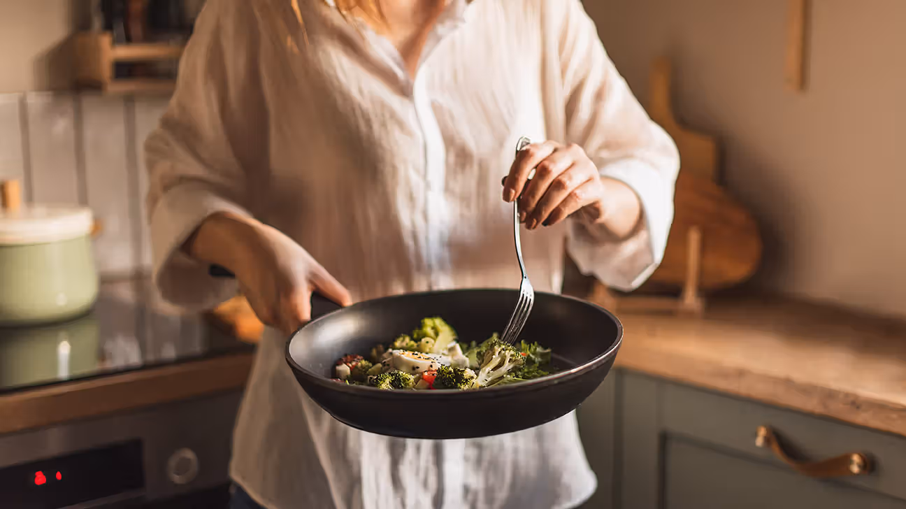 Femme cuisinant des légumes frais dans une poêle