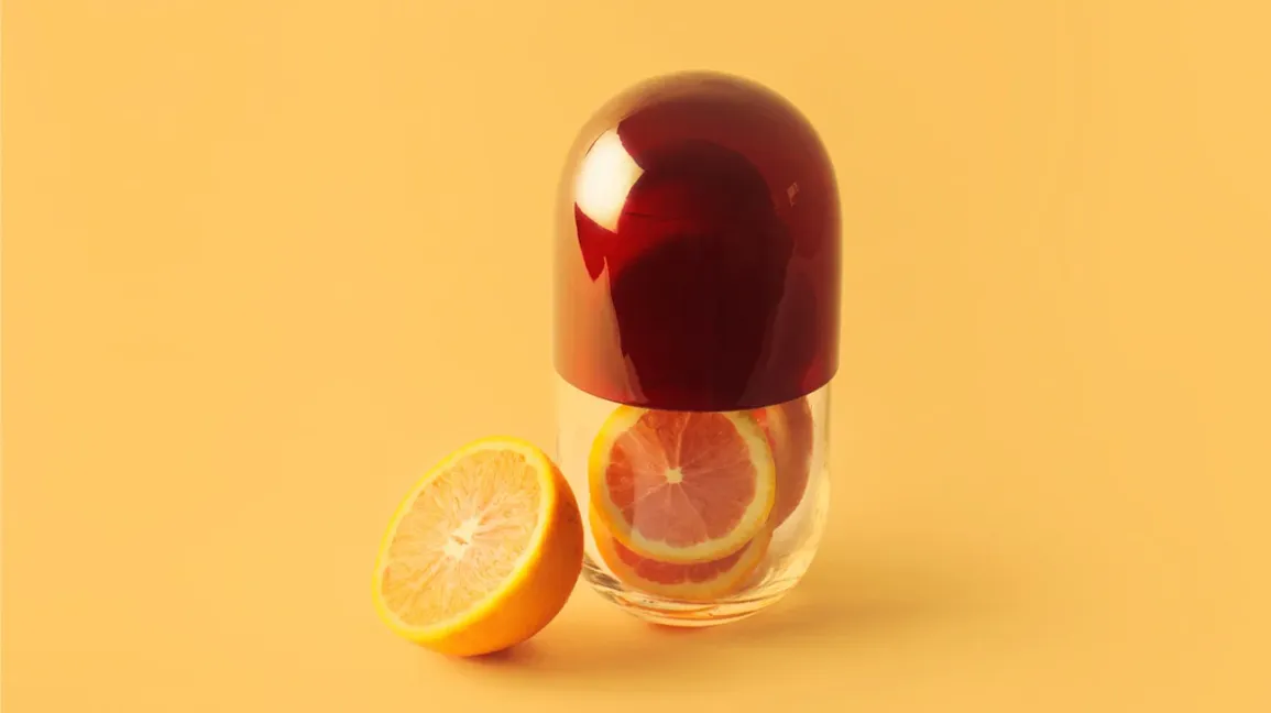 Une orange tranchée à l'intérieur d'une gélule géante illustrant la vitamine C
